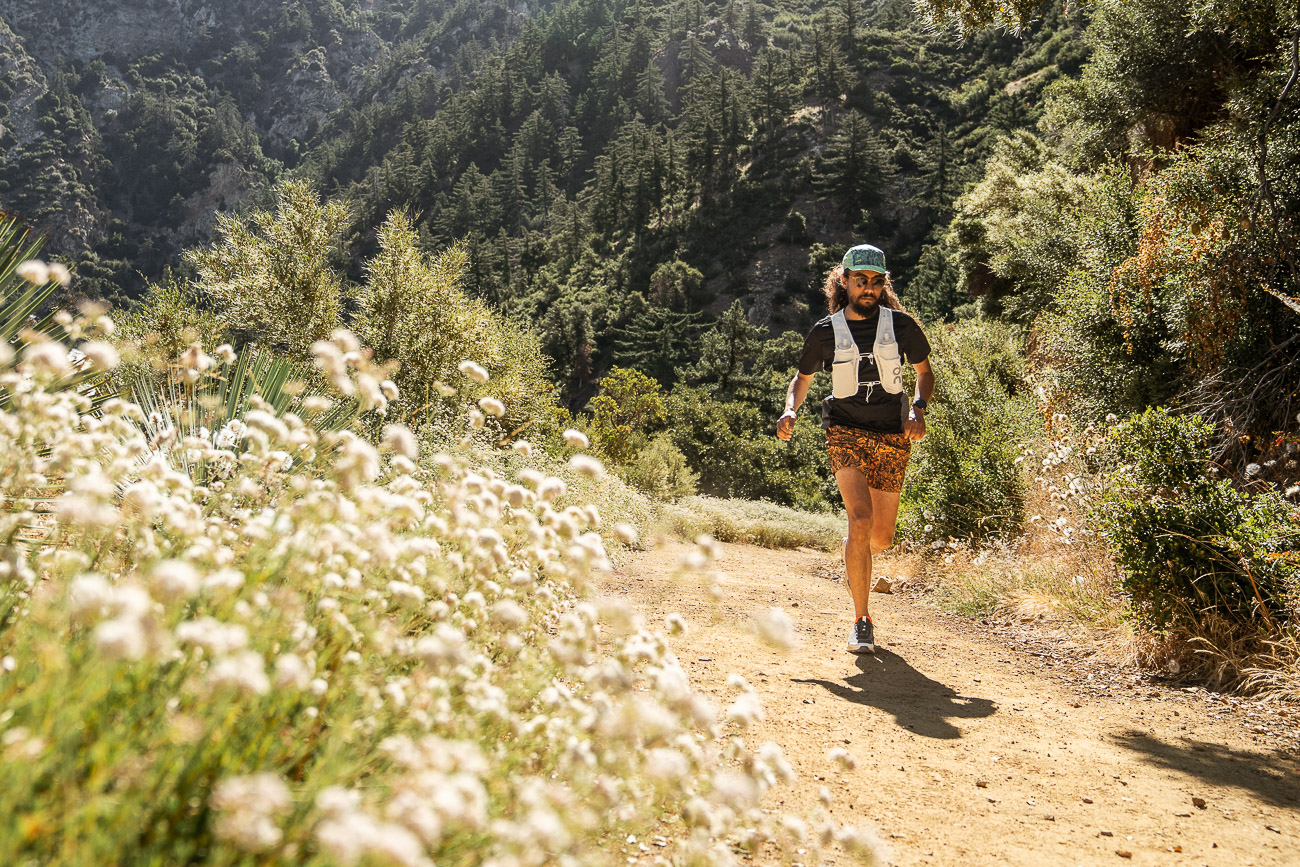runner on trail in mountains with spring flowers